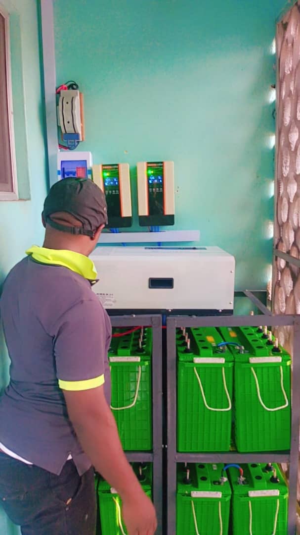 Technician beside a large battery bank and inverter